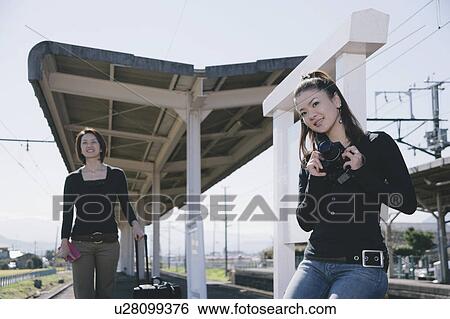 Two young women waiting for train on train platform View Large Photo Image Stock Photograph - Two young women waiting for train on train platform. Fotosearch