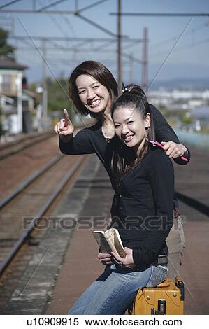 Two young women waiting for train on train platform View Large Photo Image Stock Photography - Two young women waiting for train on train platform. Fotosearch