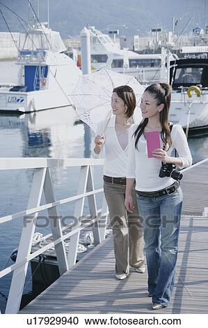 Stock Image - Two young women walking on pier. Fotosearch