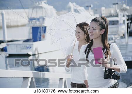 Two young women walking on pier View Large Photo Image Stock Photograph - Two young women walking on pier. Fotosearch