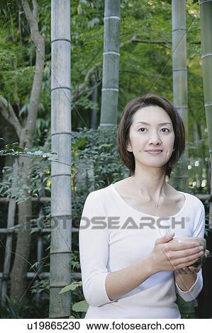 Stock Image - Young woman drinking green tea. Fotosearch