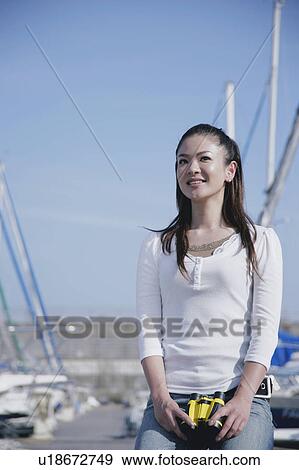 Stock Photo - Young woman sitting in marina. Fotosearch