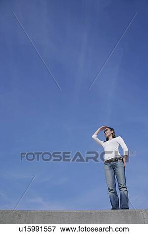Stock Photo - Young woman standing on breakwater. Fotosearch