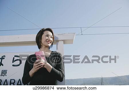 Picture - Young woman standing on train platform. Fotosearch