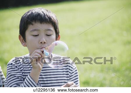 Stock Photograph - Boy blowing bubbles. Fotosearch