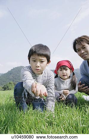 Stock Image - Family catching insects in meadow. Fotosearch
