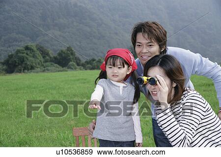 Stock Photo - Family having picnic, mother using binoculars. Fotosearch