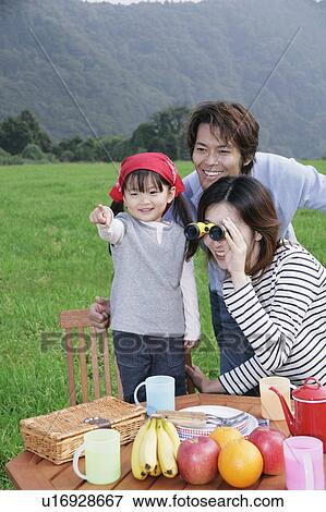 Stock Photo - Family having picnic, mother using binoculars. Fotosearch
