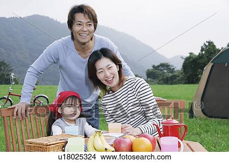 Picture - Family sitting at picnic table. Fotosearch