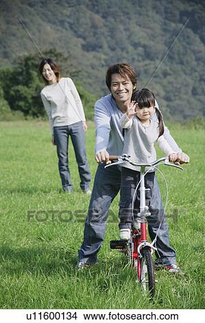Father and daughter riding bike in meadow View Large Photo Image Picture - Father and daughter riding bike in meadow. Fotosearch