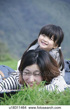 Mother and daughter lying down on ground View Large Photo Image Picture - Mother and daughter lying down on ground. Fotosearch