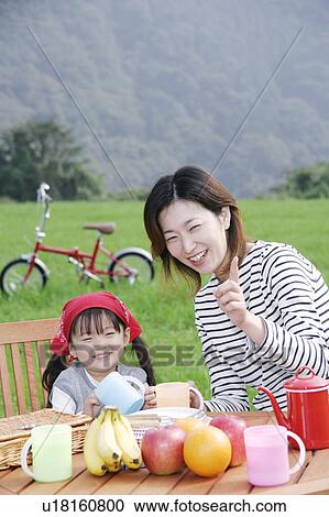Stock Image - Mother and daughter sitting at picnic table. Fotosearch