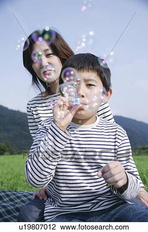Stock Image - Mother and son blowing bubbles. Fotosearch