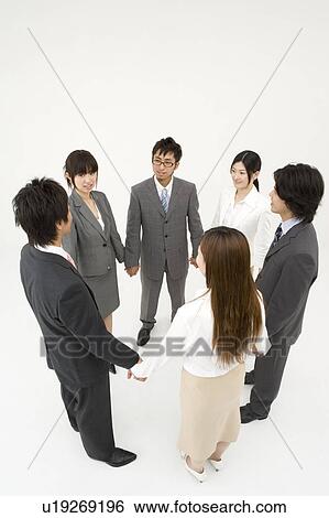 Stock Photograph - Business people standing in circle holding hands. Fotosearch