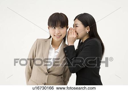 Stock Photograph - Businesswoman whispering to her colleague. Fotosearch