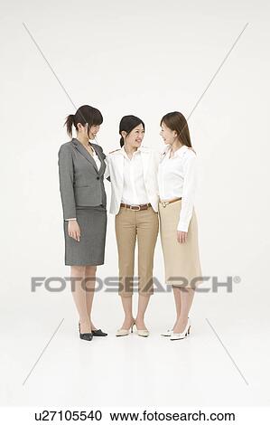 Stock Image - Three businesswomen standing with arms around each other. Fotosearch