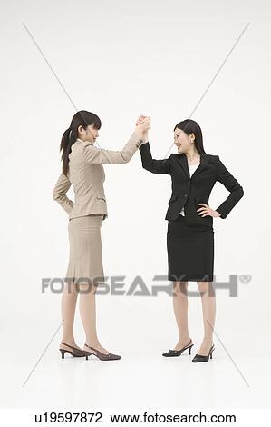 Stock Image - Two businesswomen shaking hands. Fotosearch