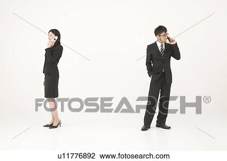 Stock Image - Two young business people talking on mobile phones. Fotosearch