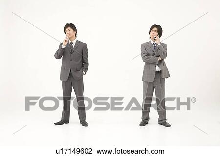 Stock Image - Two young businessmen talking on mobile phones. Fotosearch
