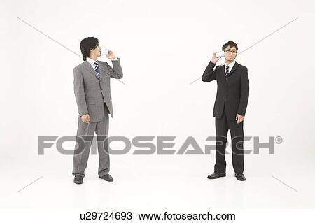 Stock Image - Two young businessmen talking with string and cups. Fotosearch