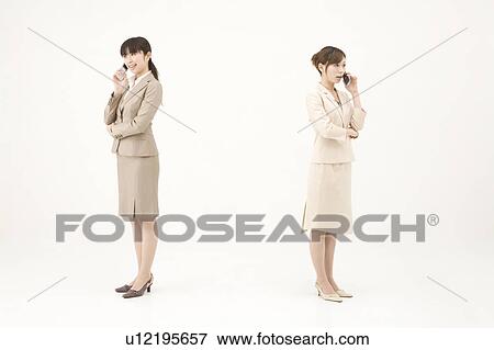 Stock Photo - Two young businesswomen talking on mobile phones. Fotosearch