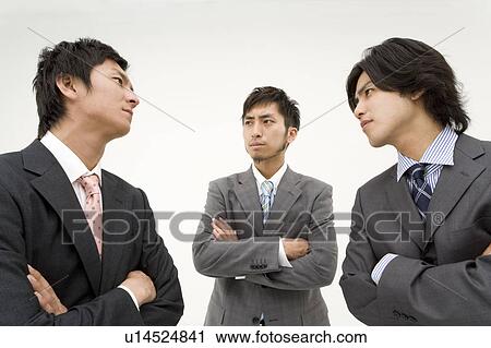 Stock Image - Three businessmen glaring at each other. Fotosearch