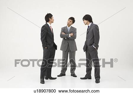 Stock Image - Three businessmen glaring at each other. Fotosearch