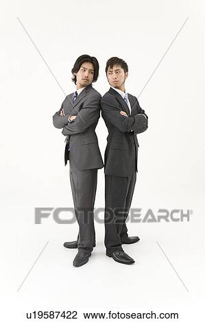 Two businessmen standing back to back View Large Photo Image Stock Image - Two businessmen standing back to back. Fotosearch