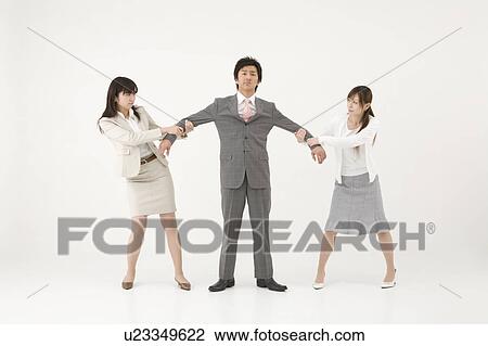 Stock Image - Two businesswomen fighting over man. Fotosearch