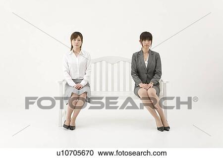 Stock Image - Two businesswomen sitting on bench. Fotosearch