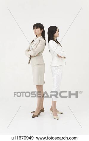 Two businesswomen standing back to back View Large Photo Image Stock Photo - Two businesswomen standing back to back. Fotosearch