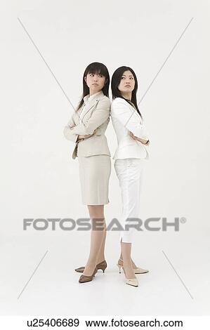 Two businesswomen standing back to back View Large Photo Image Stock Photo - Two businesswomen standing back to back. Fotosearch