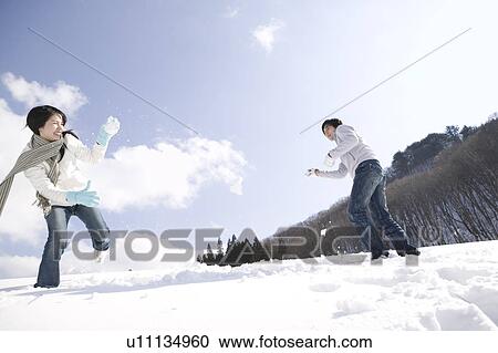 Stock Image - Young couple having snowball fight. Fotosearch