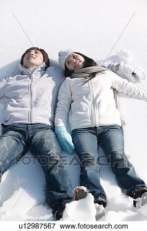 Stock Photo - Young couple lying on snow. Fotosearch