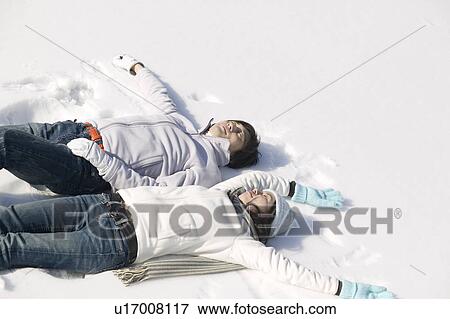 Young couple lying on snow View Large Photo Image Stock Photo - Young couple lying on snow. Fotosearch