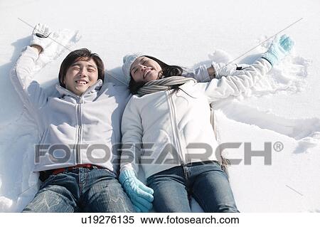 Stock Photography - Young couple lying on snow. Fotosearch