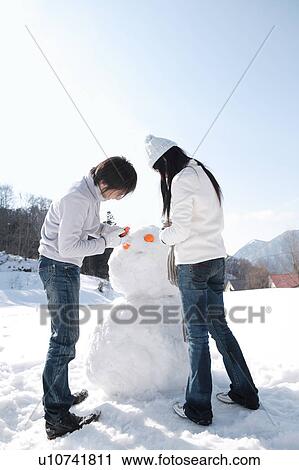 Young couple making snowman View Large Photo Image Stock Image - Young couple making snowman. Fotosearch