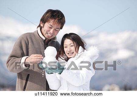 Stock Image - Young couple playing with snow. Fotosearch