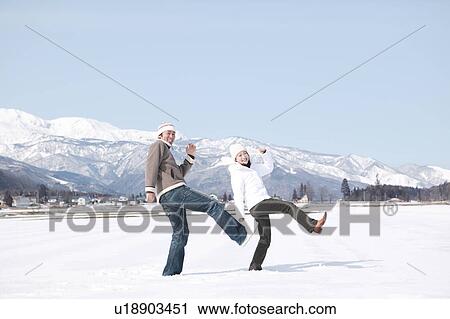 Stock Image - Young couple standing in snow. Fotosearch