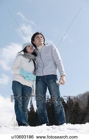 Stock Photograph - Young couple standing in snow. Fotosearch