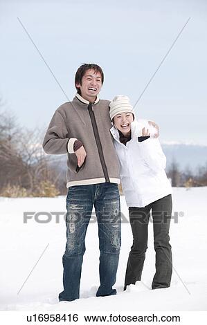 Stock Photograph - Young couple standing in snow. Fotosearch