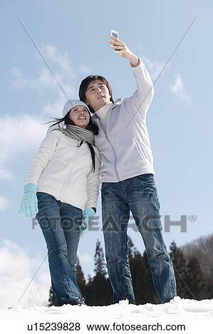 Stock Photo - Young couple taking photo with mobile phone. Fotosearch