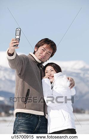 Young couple taking photo with mobile phone View Large Photo Image Stock Photography - Young couple taking photo with mobile phone. Fotosearch