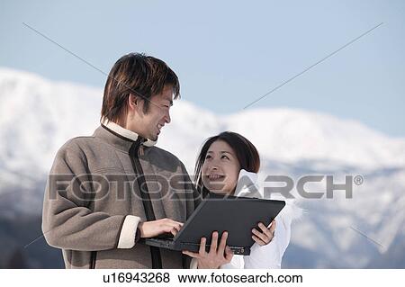 Stock Photo - Young couple using computer outside. Fotosearch