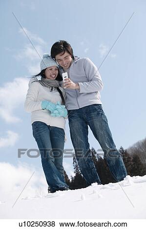 Stock Photo - Young couple using mobile phone. Fotosearch