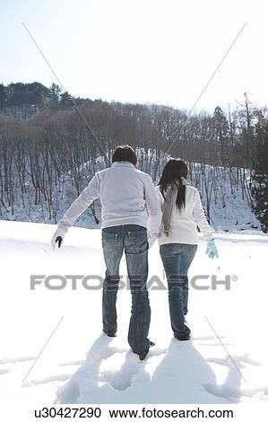 Stock Image - Young couple walking in snow. Fotosearch