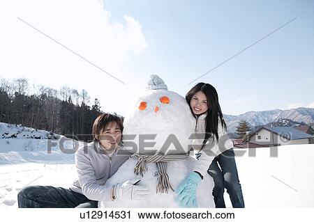 Stock Image - Young couple with snowman. Fotosearch