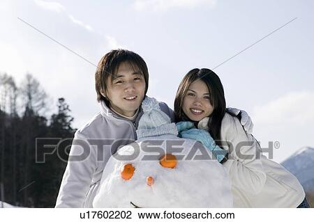 Stock Image - Young couple with snowman. Fotosearch
