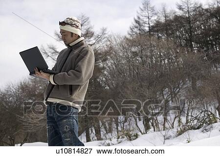 Young man using computer outside View Large Photo Image Stock Photo - Young man using computer outside. Fotosearch