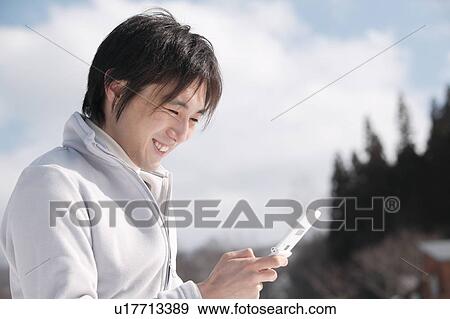 Stock Photo - Young man using mobile phone. Fotosearch